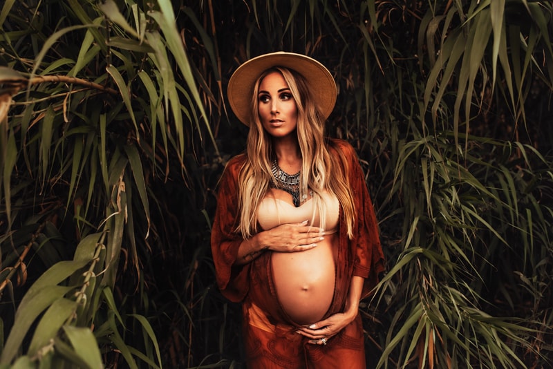 Bay Area Maternity Photography, mother standing around plants with her hands around her belly