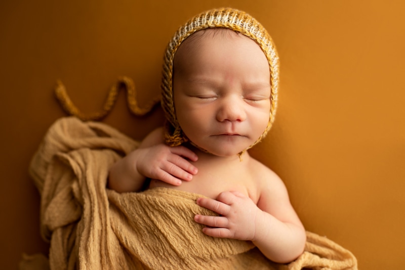 Bay Area Newborn Photography, baby in yellow bonnet on orange background