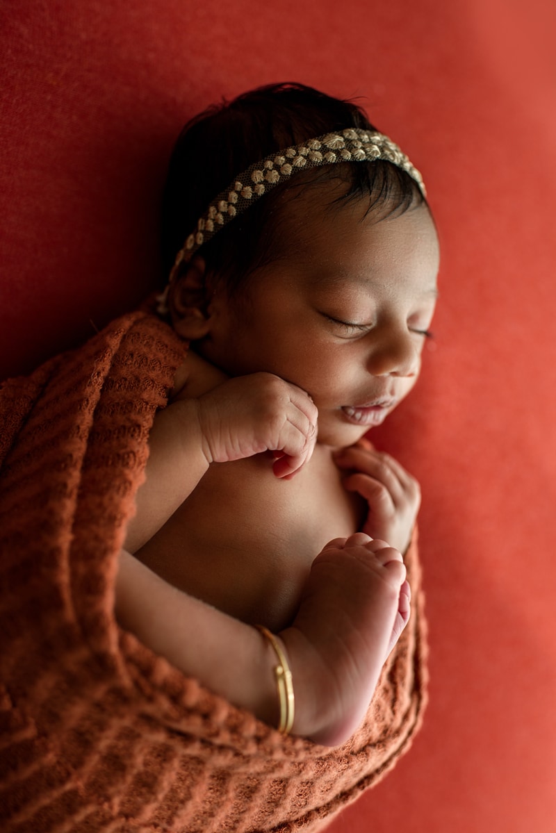 Bay Area Newborn Photography, baby sleeping on red background with gold rhinestone headband